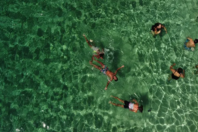 Aerial view of swimmers in the crystal-clear water of Salt Whistle Bay, Mayreau